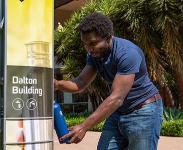 Man filling up drink bottle from UNSW bubbler on University Mall