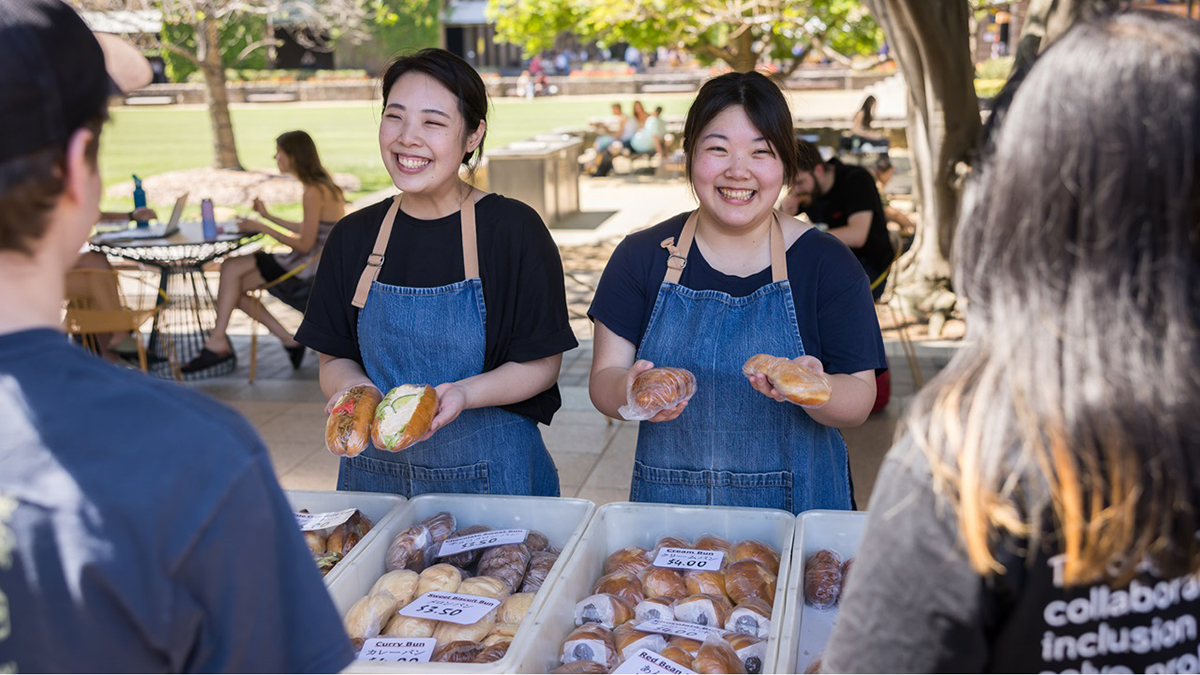 Two women smiling as they serve food during Languages Festival