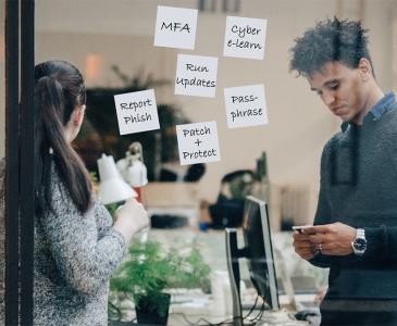 A group of people behind a window covered in notes featuring words related to cyber security