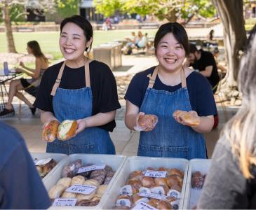 Two women smiling as they serve food during Languages Festival