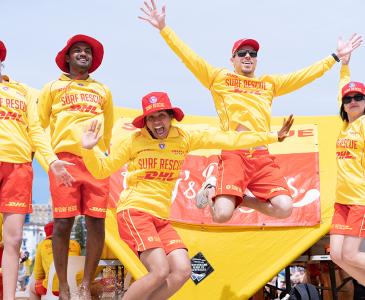 A group of five people dressed in surf rescue outfits jumping in the air